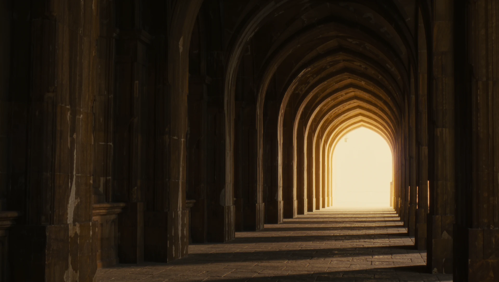 A long dark corridor opening into brilliant warm light at its end, silhouetted stone arches framing the view